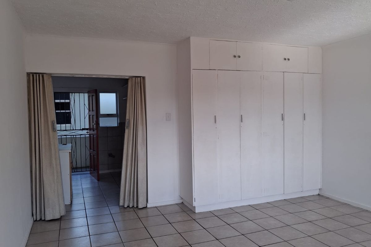A spacious bedroom featuring built-in cupboards and ceramic floor tiles, offering a blank canvas for personalization.