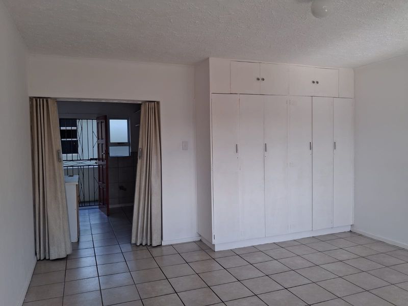 A spacious bedroom featuring built-in cupboards and ceramic floor tiles, offering a blank canvas for personalization.