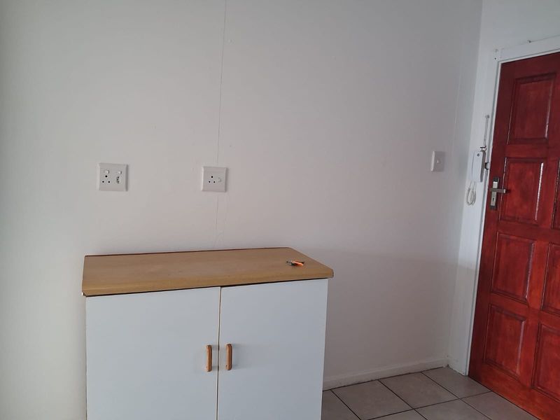 An entry area featuring tiled flooring, a built-in storage cabinet, and an intercom system near the wooden entrance door.