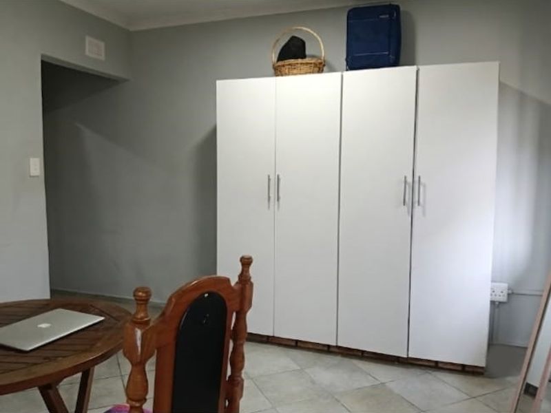 A bedroom featuring tiled flooring and a large white built-in wardrobe with modern handles.