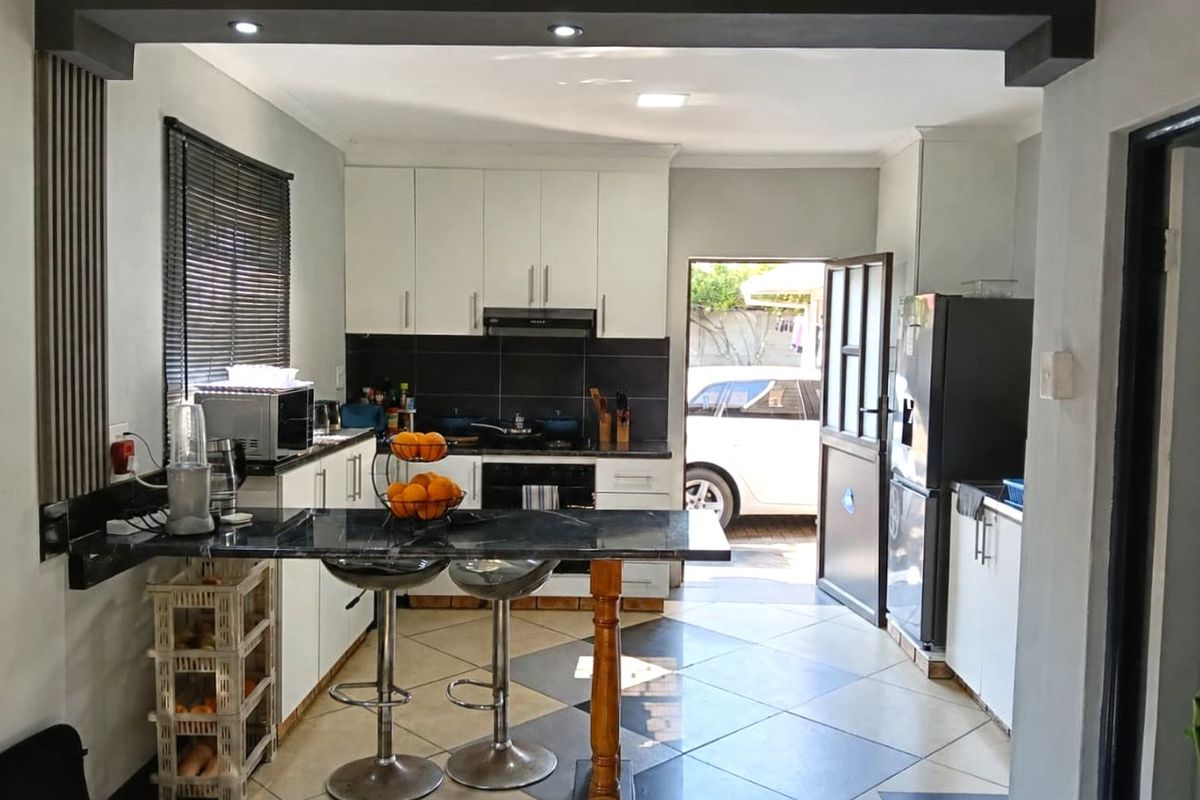 Modern kitchen featuring white cabinetry, dark countertops, a breakfast bar, and direct access to the exterior, creating a functional and open cooking space.
