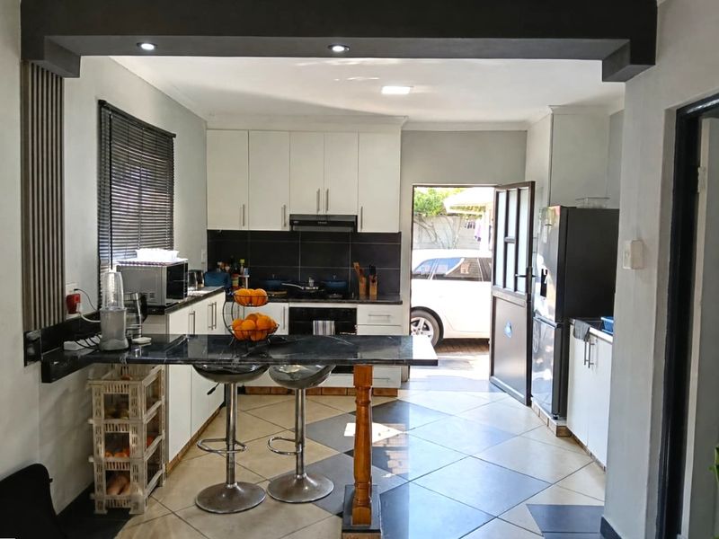 Modern kitchen featuring white cabinetry, dark countertops, a breakfast bar, and direct access to the exterior, creating a functional and open cooking space.