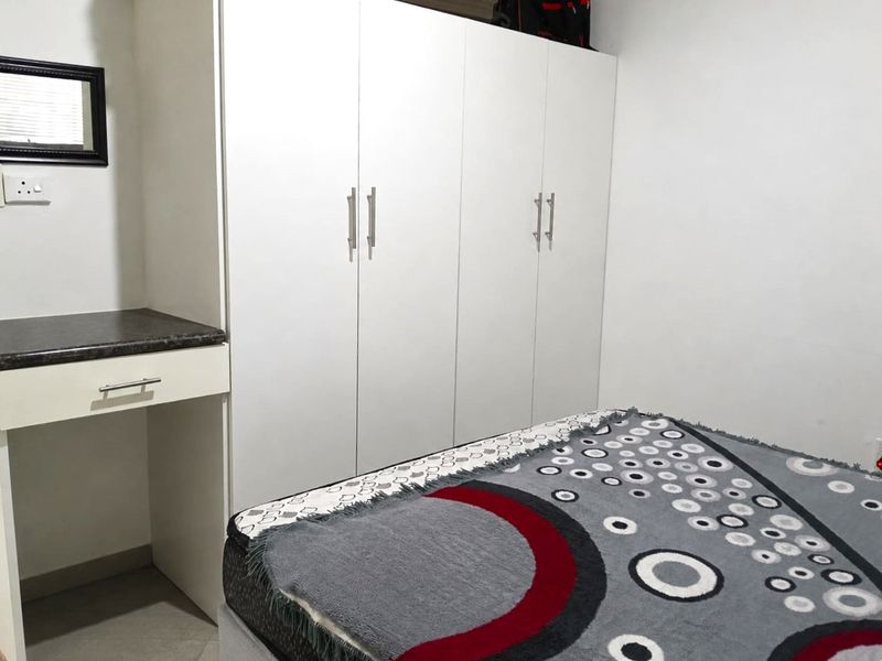 A bedroom featuring a white built-in wardrobe and a matching built-in vanity unit with a dark countertop.