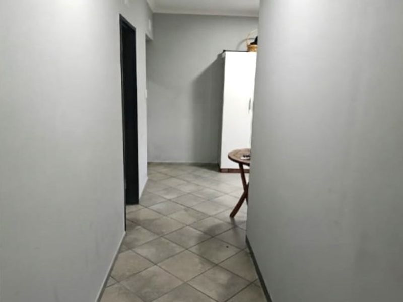A functional hallway featuring neutral grey walls and diamond-patterned floor tiles, providing access to adjacent rooms within the cottage.