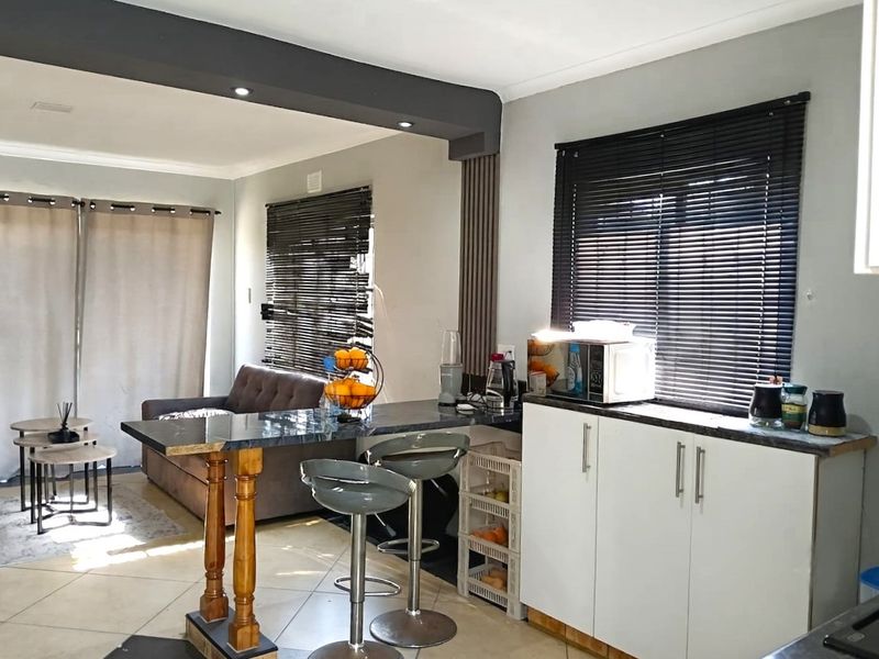Open plan kitchen and living area featuring a breakfast bar, modern cabinetry, tiled flooring, and recessed lighting.