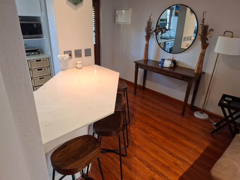 Open plan living area featuring a stone breakfast bar, warm laminate flooring, and a functional kitchen nook with built-in microwave.