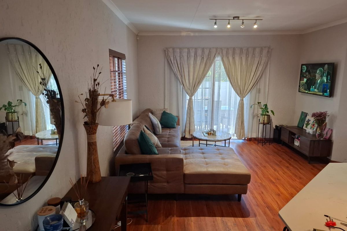 A comfortable living room featuring warm laminate flooring, track lighting, and a sliding glass door providing access to the outdoor area.