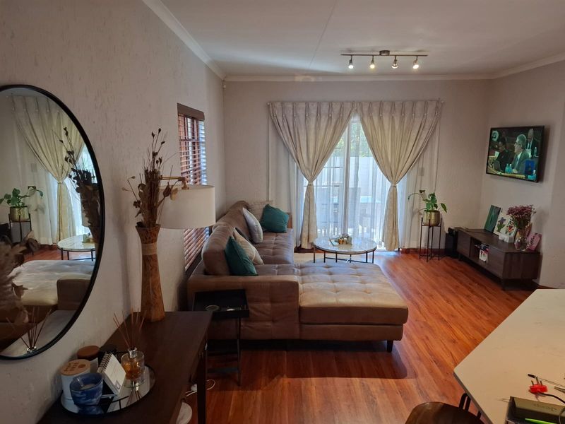 A comfortable living room featuring warm laminate flooring, track lighting, and a sliding glass door providing access to the outdoor area.