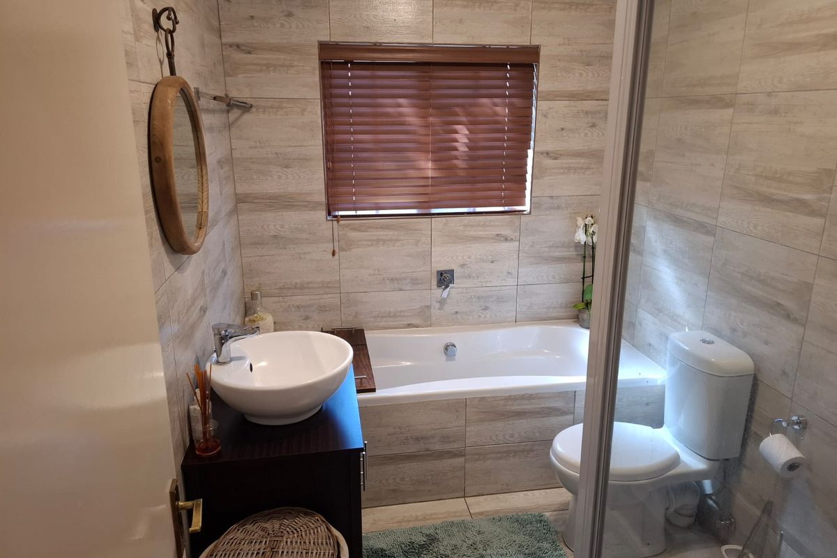 A modern bathroom featuring a built-in bathtub, a vessel sink vanity, and neutral wood-look wall tiling, creating a clean and functional space.