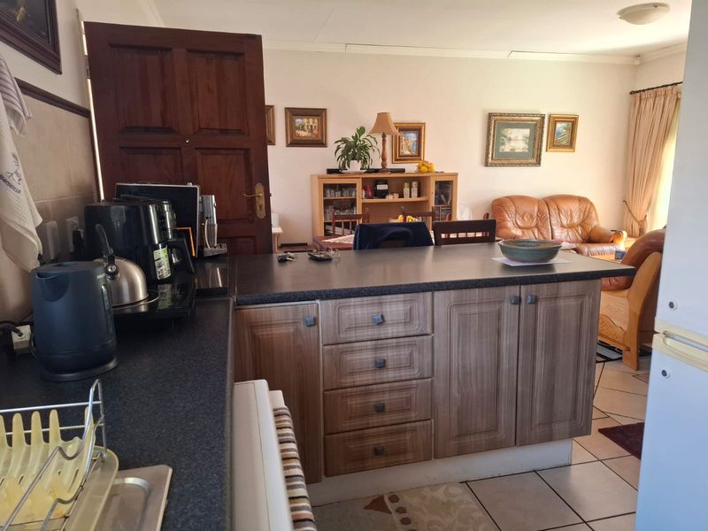Open plan kitchen and living area featuring laminate cabinetry, dark countertops, and ceramic floor tiles in a functional, lived-in townhouse layout.