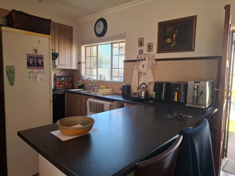 A functional kitchen featuring laminate cabinetry, dark countertops, a breakfast bar, and a tiled backsplash, providing a practical workspace for daily meal preparation.