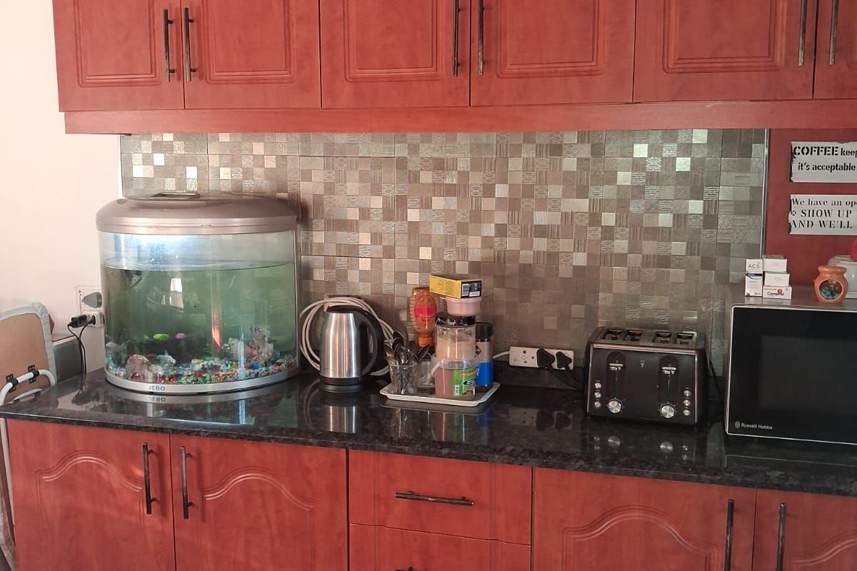 A functional kitchen featuring warm-toned laminate cabinetry, dark granite countertops, and a decorative mosaic tile backsplash.