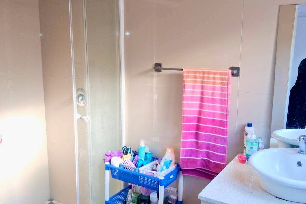 A functional bathroom featuring a glass shower enclosure, a modern vessel sink with vanity storage, and neutral wall tiling.
