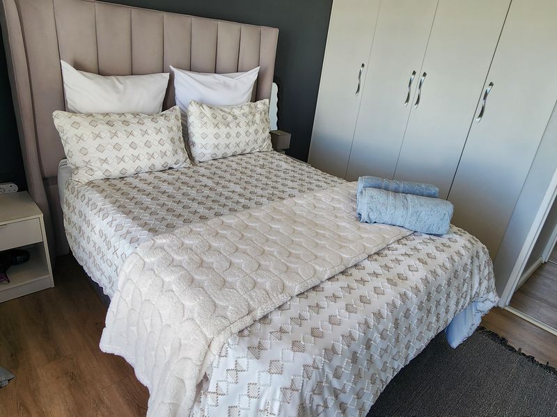 A well-maintained bedroom featuring laminate flooring and built-in cupboards, offering a clean and functional living space.