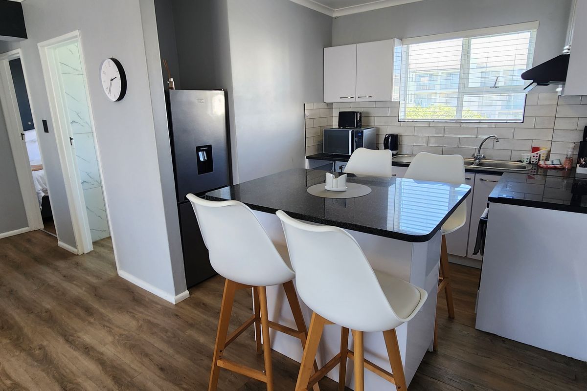 A modern kitchen featuring granite countertops, subway tile backsplash, and white cabinetry, seamlessly integrated with a breakfast bar area.