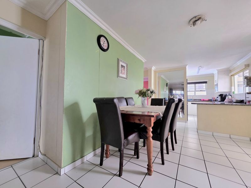 Open-plan dining area flowing into a functional kitchen with granite countertops and tiled flooring, offering a practical layout for daily living.