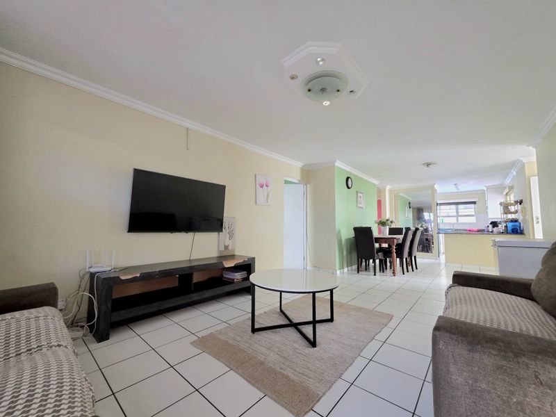 Open-plan living and dining area featuring tiled flooring, coving, and a connected kitchen space, offering a functional layout for modern townhouse living.