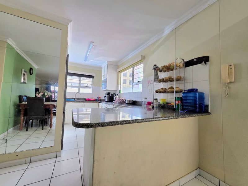 Functional kitchen featuring granite countertops, tiled backsplash, and ample built-in cabinetry, offering a practical layout for daily meal preparation.