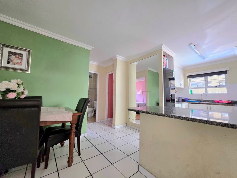 Open-plan kitchen and dining area featuring granite countertops, tiled flooring, and neutral cabinetry, providing a functional layout for daily living.