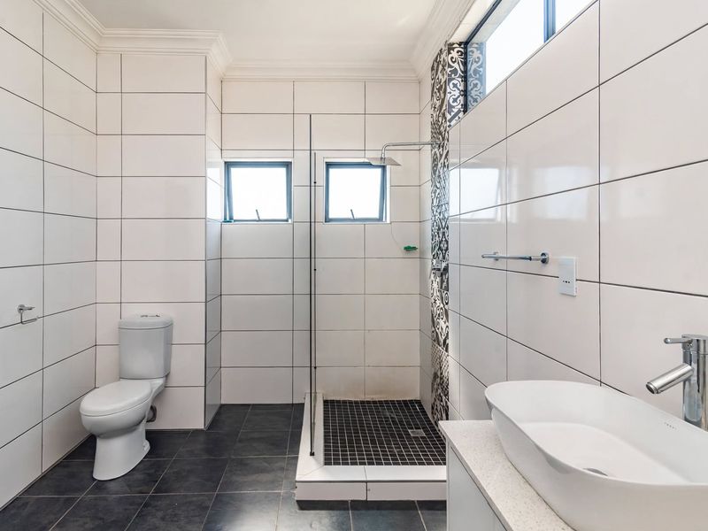 Modern bathroom featuring a walk-in shower with glass screen, vessel sink vanity, and contemporary tiled finishes throughout.