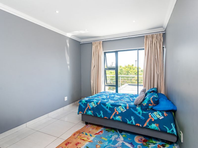 A bright bedroom featuring tiled flooring, recessed downlights, and a sliding glass door providing access to an outdoor area.