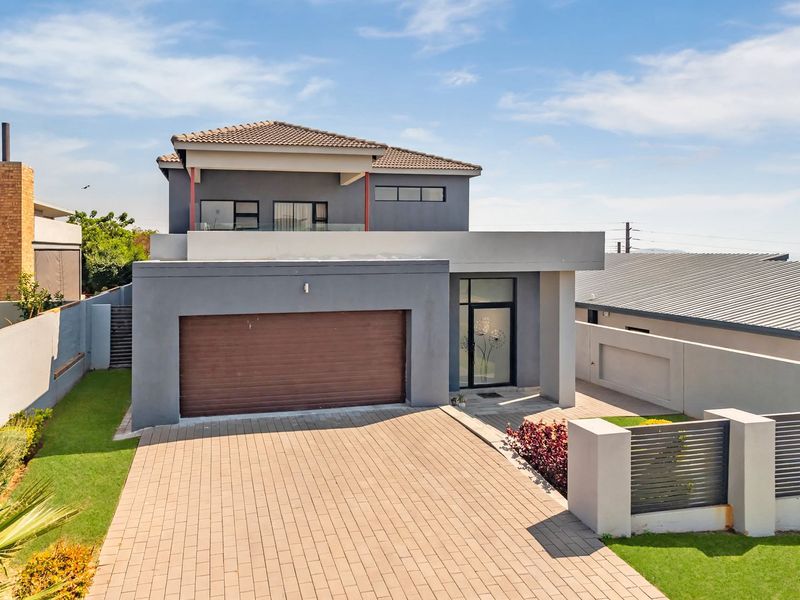 Modern double-story residential home featuring a paved driveway, double garage, and a balcony with a glass balustrade.