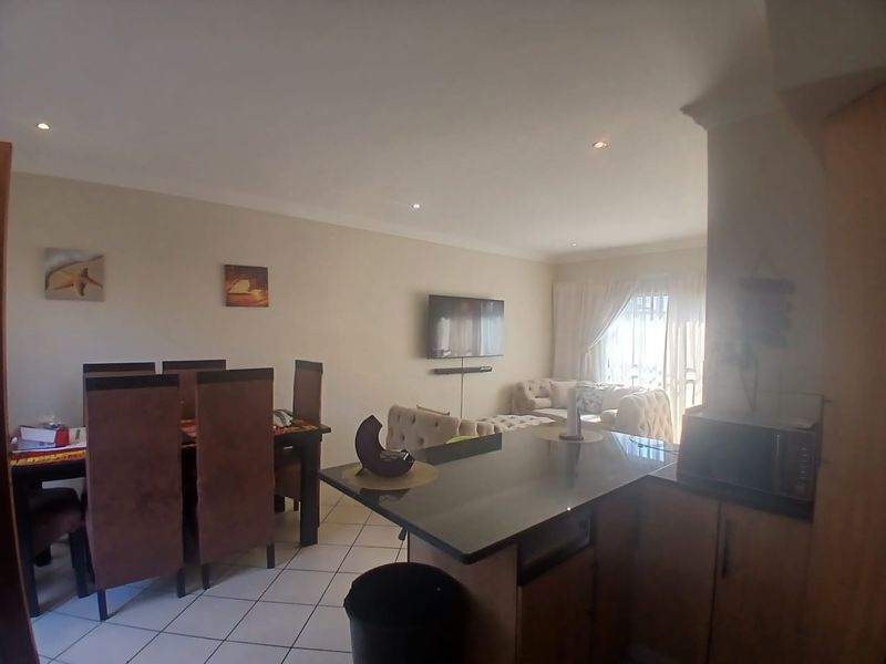 Open-plan living and dining area featuring a kitchen island with granite countertops, tiled flooring, and recessed lighting, creating a functional and connected living space.
