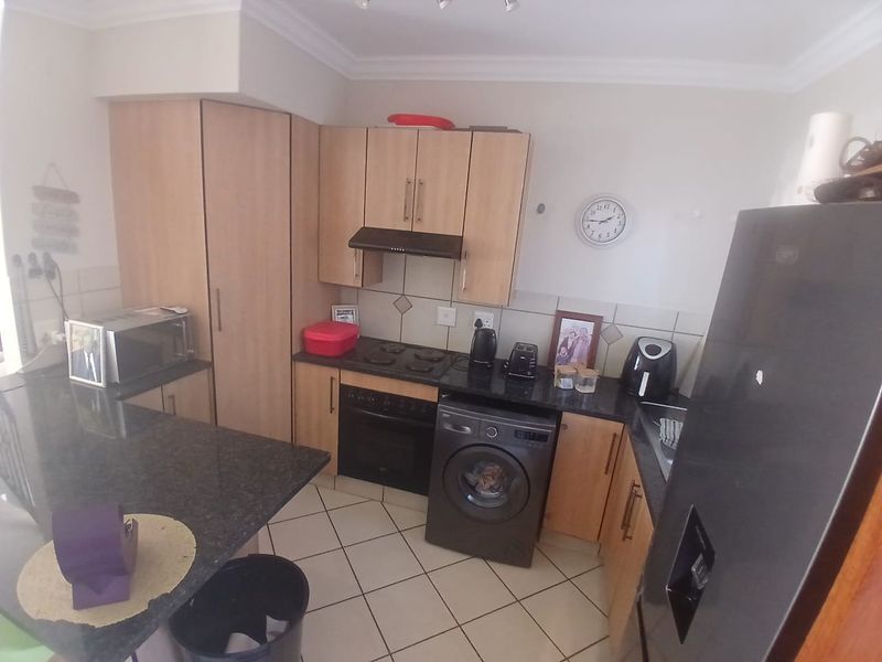 A functional kitchen featuring laminate cabinetry, granite countertops, built-in oven, electric hob, and tiled flooring, offering a practical layout for daily meal preparation.