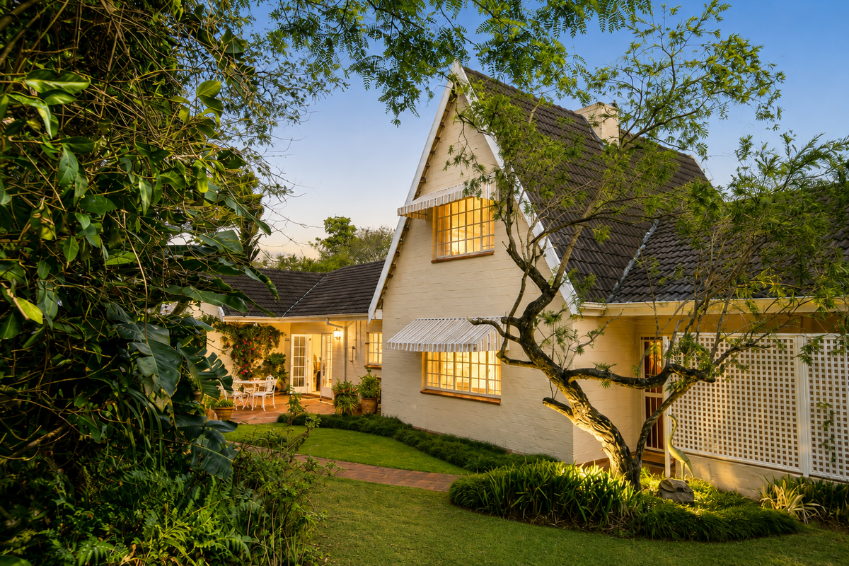 A charming rear exterior view of a house featuring a pitched tiled roof, brick facade, and a well-maintained garden with a paved walkway.