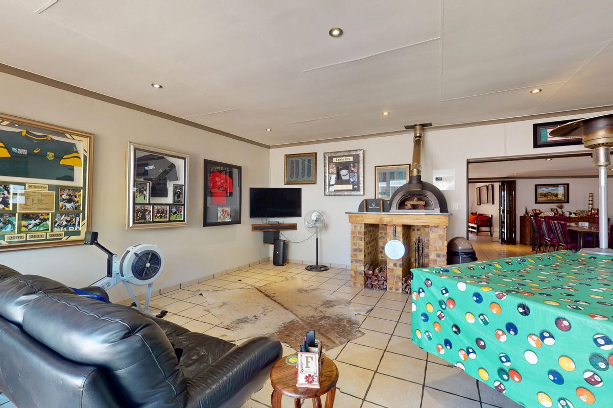 Spacious living area featuring a built-in brick fireplace, recessed downlighting, and tiled flooring, offering a versatile space for relaxation and entertainment.