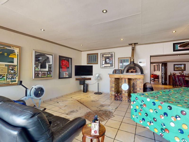 Spacious living area featuring a built-in brick fireplace, recessed downlighting, and tiled flooring, offering a versatile space for relaxation and entertainment.