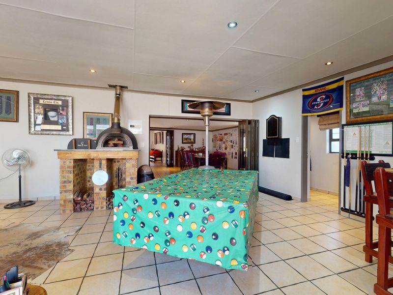 Spacious living area featuring a built-in brick pizza oven, tiled flooring, and recessed lighting, with bi-fold doors leading to an adjacent room.