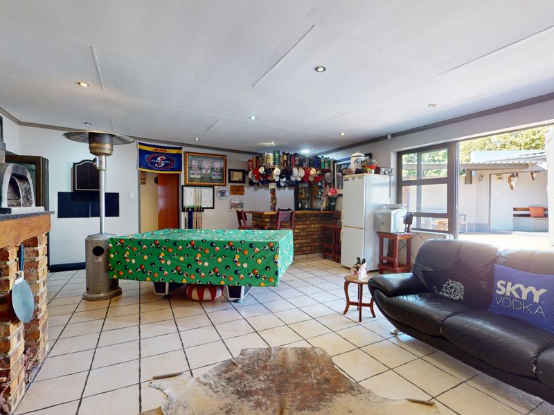 Spacious living area featuring a built-in brick fireplace, tiled flooring, and a built-in bar, with direct access to the outdoor patio area.