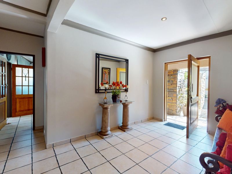 A bright and welcoming entrance hall featuring neutral wall tones, tiled flooring, and direct access to the exterior through a timber-framed door.