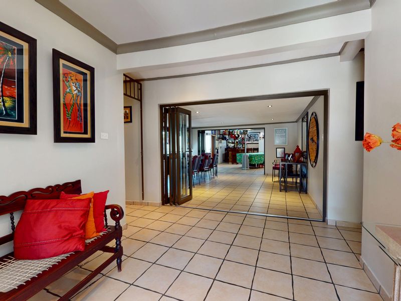 Welcoming entrance hall featuring tiled flooring and bi-fold doors leading through to an open-plan living and entertainment area.