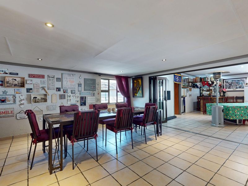 Open plan living and dining area featuring tiled flooring, recessed lighting, and sliding glass doors leading to an adjacent bar area.