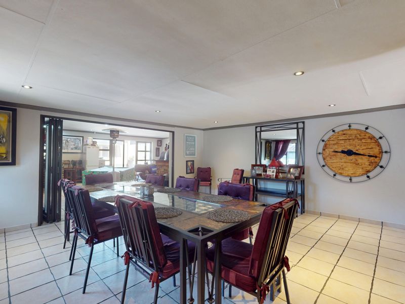 Spacious dining room featuring neutral tiled flooring, recessed downlighting, and bi-fold doors leading to an adjacent living area.