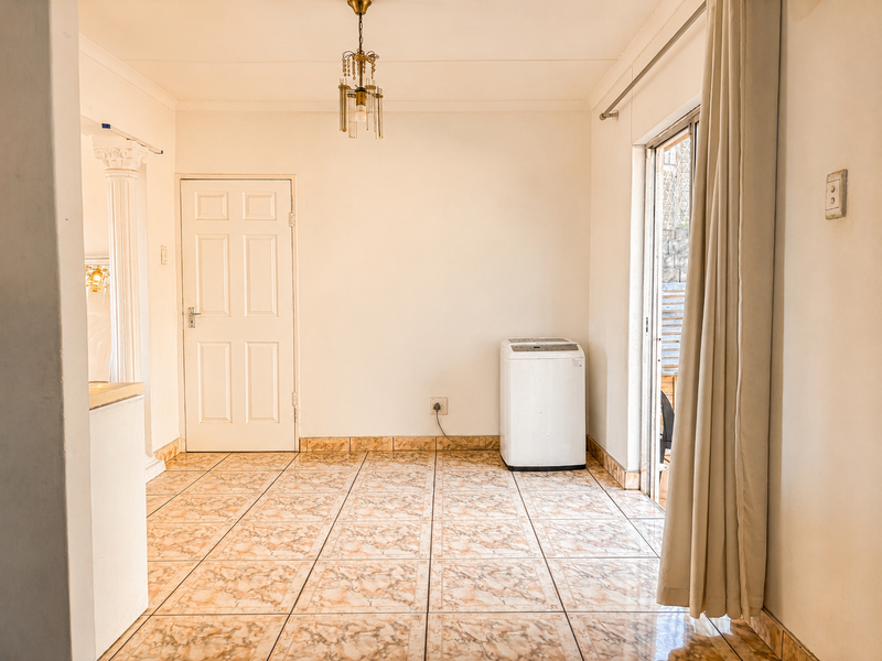 An empty living area featuring tiled flooring, a sliding glass door providing outdoor access, and a neutral interior finish.