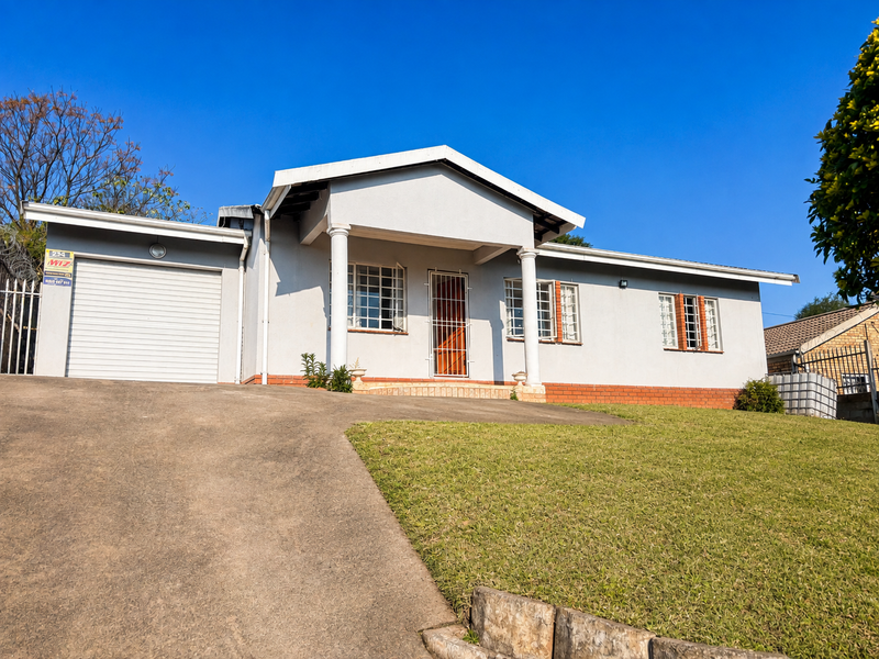 Front elevation of a single-story house featuring a concrete driveway, integrated garage, and security-fitted windows and entrance.