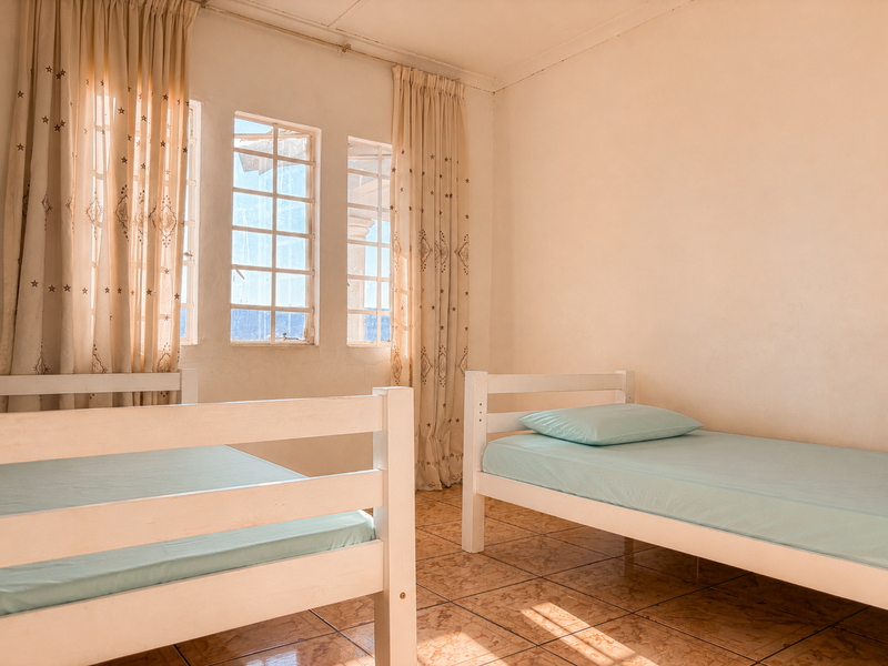 A bedroom featuring tiled flooring and grid-style windows, providing a functional space with potential for cosmetic updates.