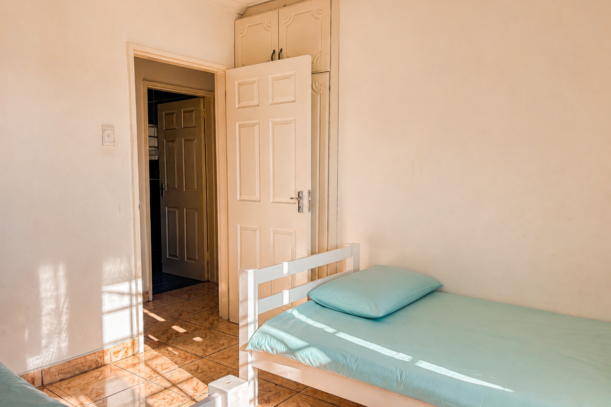 A bedroom featuring built-in cupboards, tiled flooring, and direct access to an adjoining room.