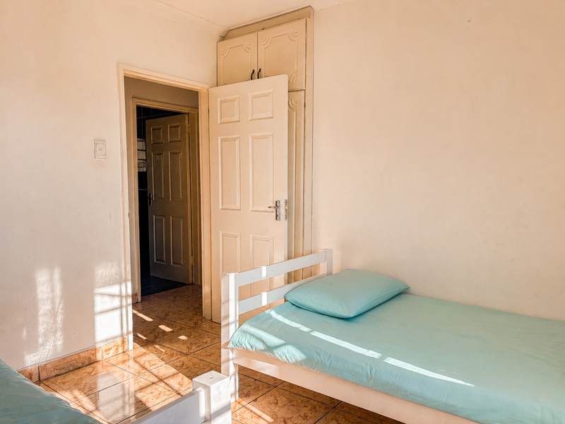 A bedroom featuring built-in cupboards, tiled flooring, and direct access to an adjoining room.