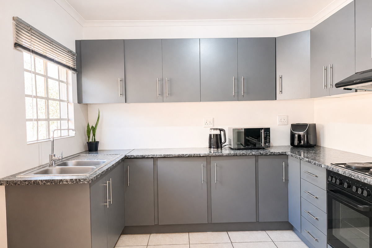 Modern kitchen featuring grey cabinetry, laminate countertops, stainless steel double sink, and integrated oven with hob and extractor fan.