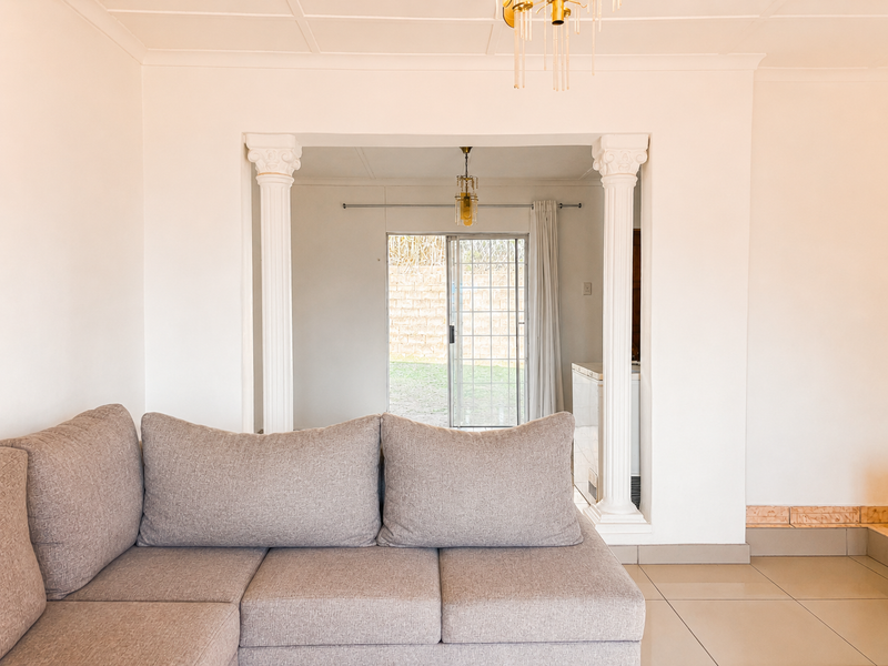 Living room featuring decorative columns leading to an adjacent space with a sliding glass door providing access to the rear exterior.