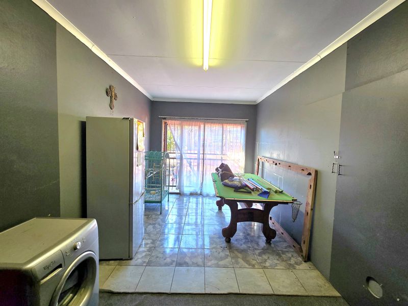 A multi-purpose living area featuring tiled flooring and a sliding glass door, providing access to the exterior.