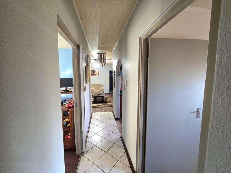 A central hallway featuring tiled flooring and an arched entryway leading into the living area, connecting multiple rooms within the home.