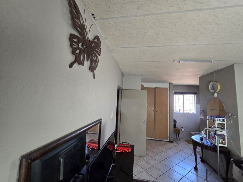 Bedroom featuring tiled flooring, built-in cupboards, and a drop ceiling. The space requires cosmetic updates to improve its overall condition and appeal.