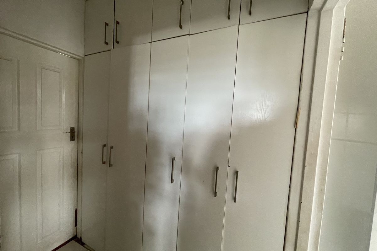 A bedroom featuring floor-to-ceiling built-in cupboards and tiled flooring, offering ample storage space.