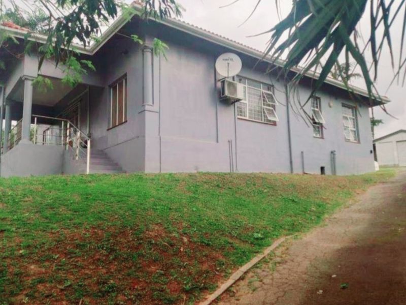 A view of the front elevation of the house featuring a covered porch, concrete stairs with metal railings, and a paved driveway.
