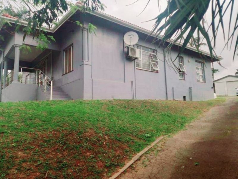 A view of the front elevation of the house featuring a covered porch, concrete driveway, and a detached garage.